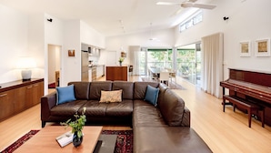 Una sala de estar moderna con un sofá modular, un piano y una zona de comedor.
