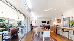 Una cocina moderna con una isla de madera, un comedor con una mesa grande y una zona de estar con un banco y sillas.