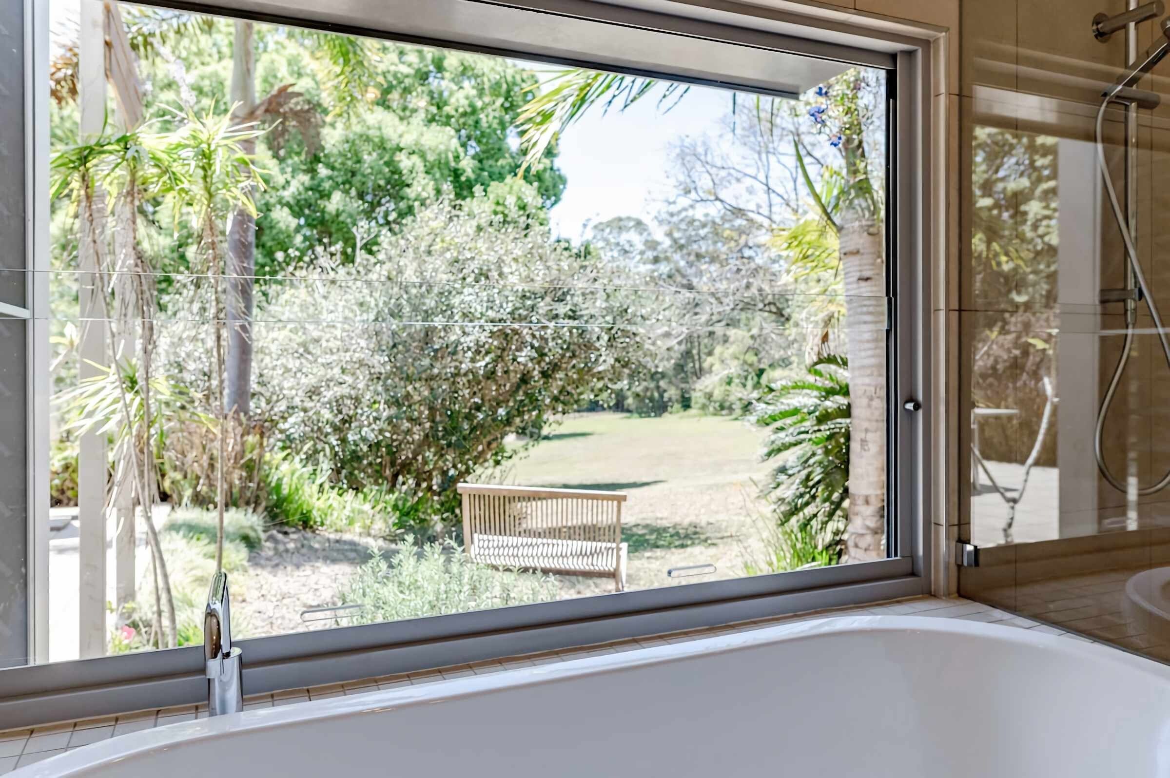 A bathroom with a large window, a bathtub, and a shower area.