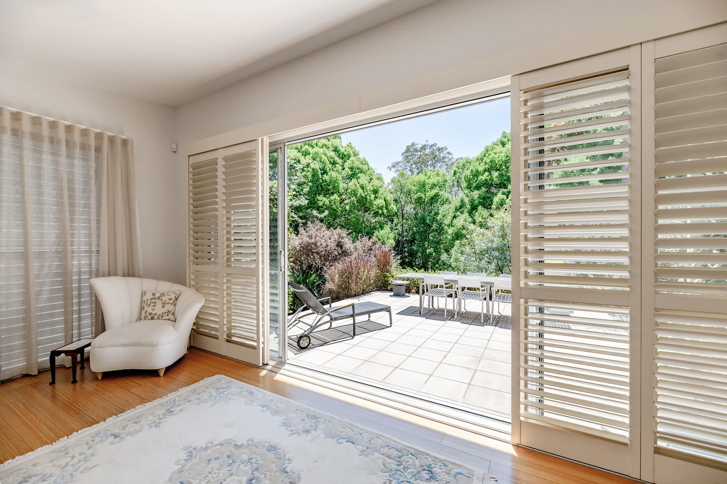 Una habitación con un sofá blanco, un tapete estampado y vistas a un patio exterior con una mesa y sillas.