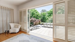 Una habitación con un sofá blanco, un tapete estampado y vistas a un patio exterior con una mesa y sillas.