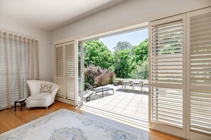 Ein Zimmer mit einem weißen Sofa, einem gemusterten Teppich und Blick auf eine Außenpatio mit Tisch und Stühlen.