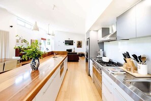 Et moderne køkken med en central ø, rustfrie stålapparater og et spiseområde med en sofa.