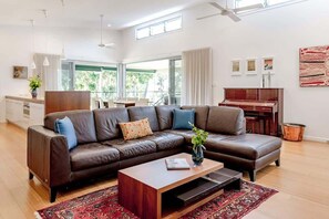 En moderne stue med en lædersofa, et træsofabord og en rød gulvtæppe med et mønster.