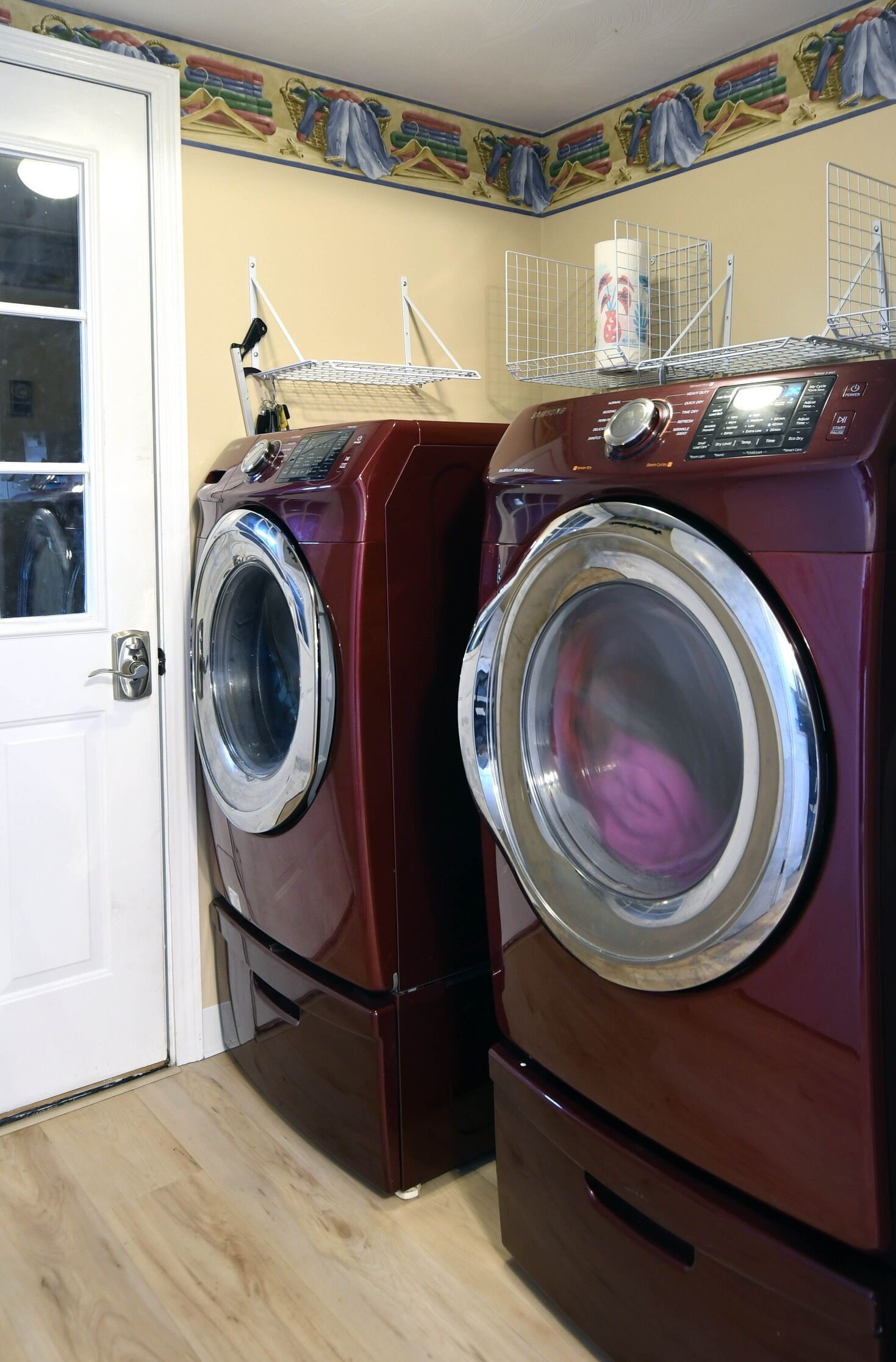 A laundry room with two stacked front-loading washing machines and a drying rack.