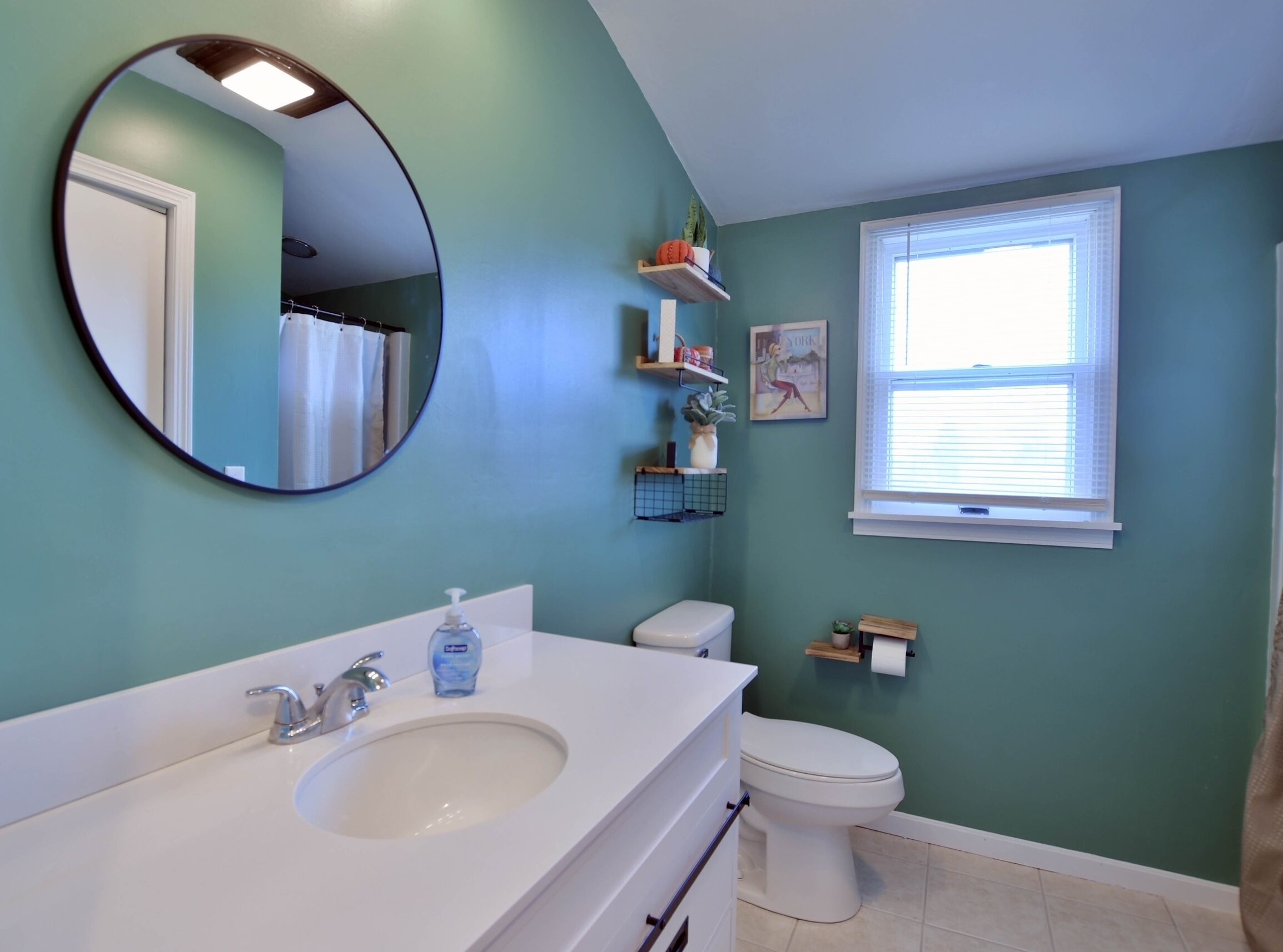 A bathroom with a white sink, a toilet, a mirror, and a window.