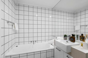 A modern bathroom with white tiles, a bathtub, a sink, and a mirror. - 8 Andari Sunshine Luxury 1min to Beach (Sunshine Beach)