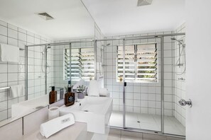 A modern bathroom with a glass-enclosed shower, a large mirror, and a white sink with toiletries. - 8 Andari Sunshine Luxury 1min to Beach (Sunshine Beach)