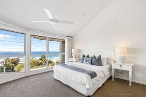 A bedroom with a bed, two bedside tables, a ceiling fan, and a large window with a view of the ocean. - 8 Andari Sunshine Luxury 1min to Beach (Sunshine Beach)