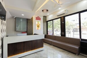 A reception area with a modern desk, a sofa, a television, and a large window offering a view of the street.