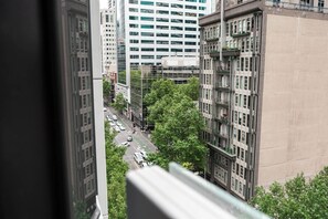 Un paisaje urbano con edificios altos, una calle con automóviles y árboles.