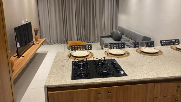 Een moderne keuken met een centraal eiland, een inbouwoven en een zithoek met een bank en stoelen.