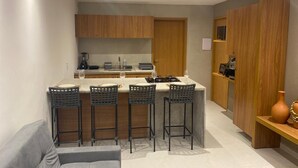 Een compacte keuken met een centraal eiland, krukken en houten keukenkastjes.