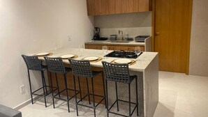 Een compacte keuken met een centraal eiland, barkrukken en een houten deur.