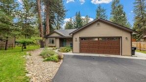 A two-story house with a garage, surrounded by trees and a well-maintained lawn. - Clean comfortable home in quiet neighborhood (McCall)