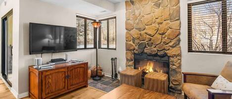 A living room with a stone fireplace, a television, and a wooden cabinet.