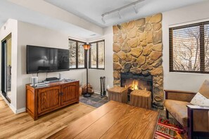 Ein Wohnzimmer mit Kamin aus Stein, einem Fernseher und einer Holzkabine.