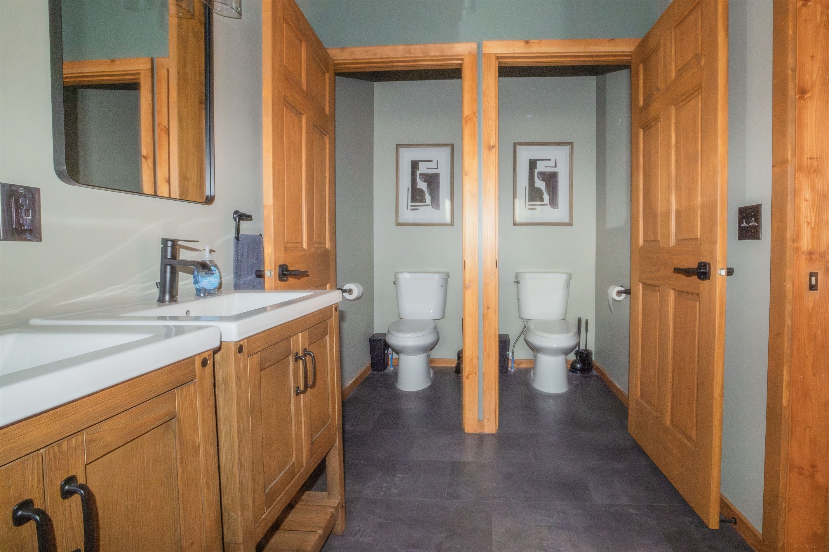 A bathroom with wooden cabinets, two toilets, and a mirror.