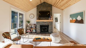 Un ampio soggiorno con camino, soffitto in legno e una grande finestra.