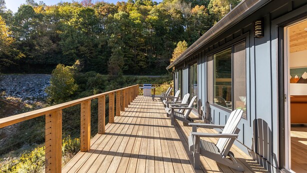 Un terrazzo in legno con sedie e vista su una zona boschiva.