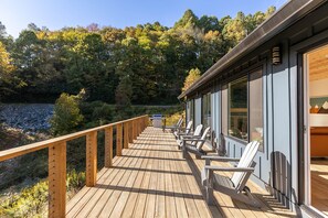 Eine Holzterrasse mit Stühlen und Blick auf ein bewaldetes Gebiet.
