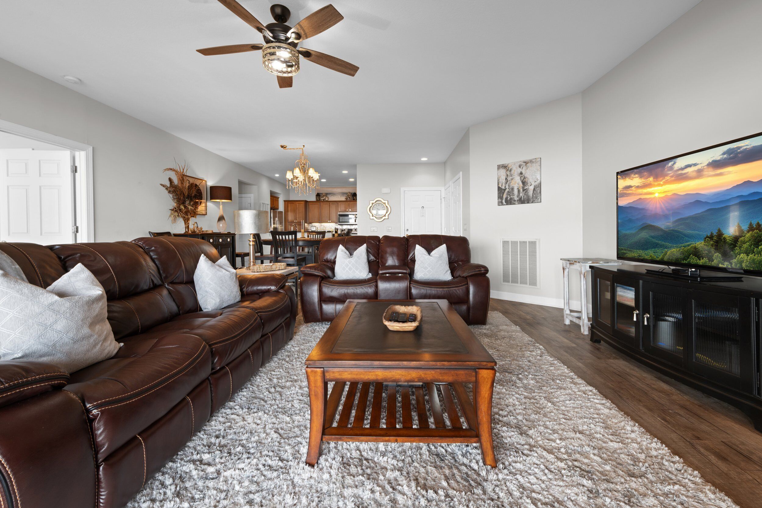 A modern living room with a brown leather sofa, a wooden coffee table, and a large flat-screen TV.