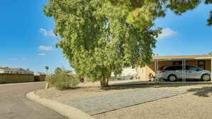 En uppfart till ett bostadshus med en parkerad bil, ett träd och en byggnad med ett garage.