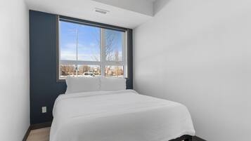 Une chambre avec une grande fenêtre, un lit et une vue sur l’extérieur.