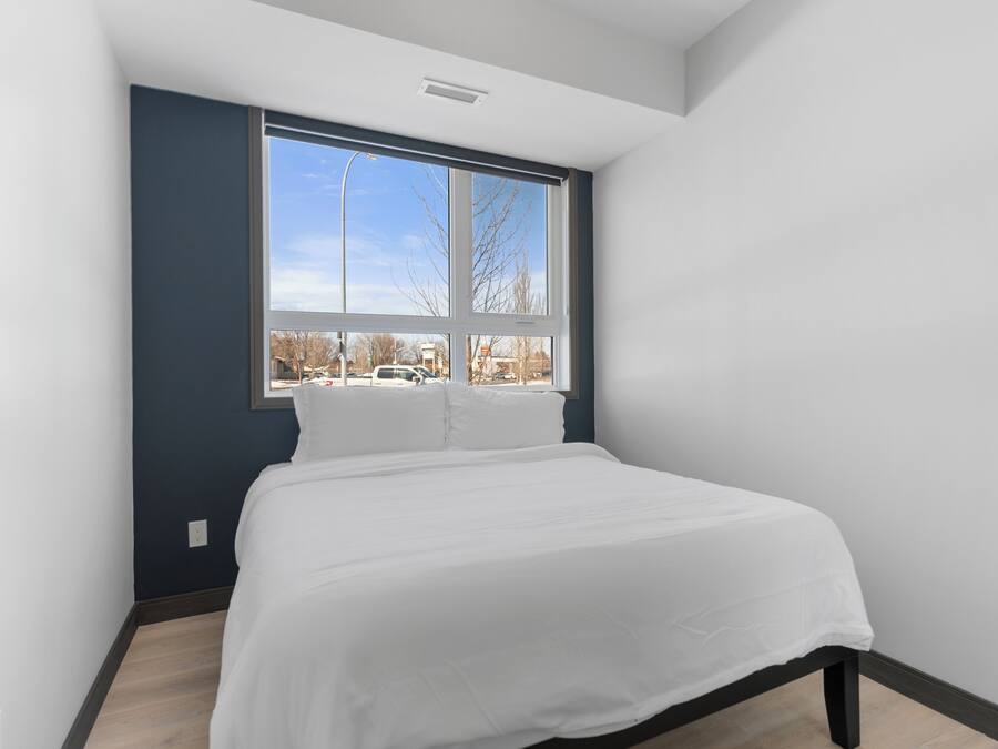 Une chambre avec une grande fenêtre, un lit et une vue sur l’extérieur.