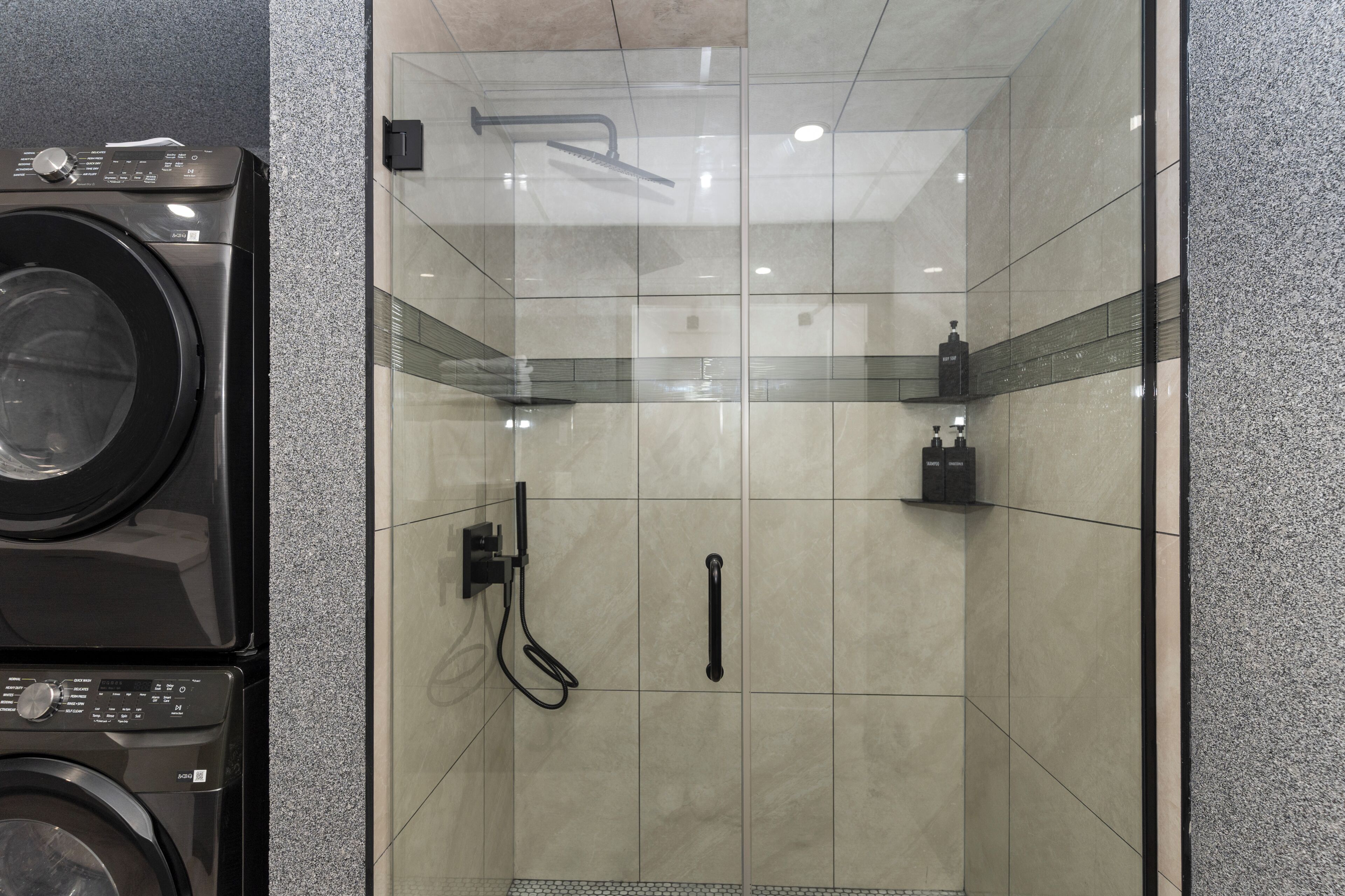 A modern bathroom with a glass-enclosed shower, a washing machine, and a towel rack.