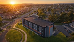 A modern building with a flat roof, surrounded by a parking lot and a road. - Lux Suites Extended Stay (Thunder Bay)