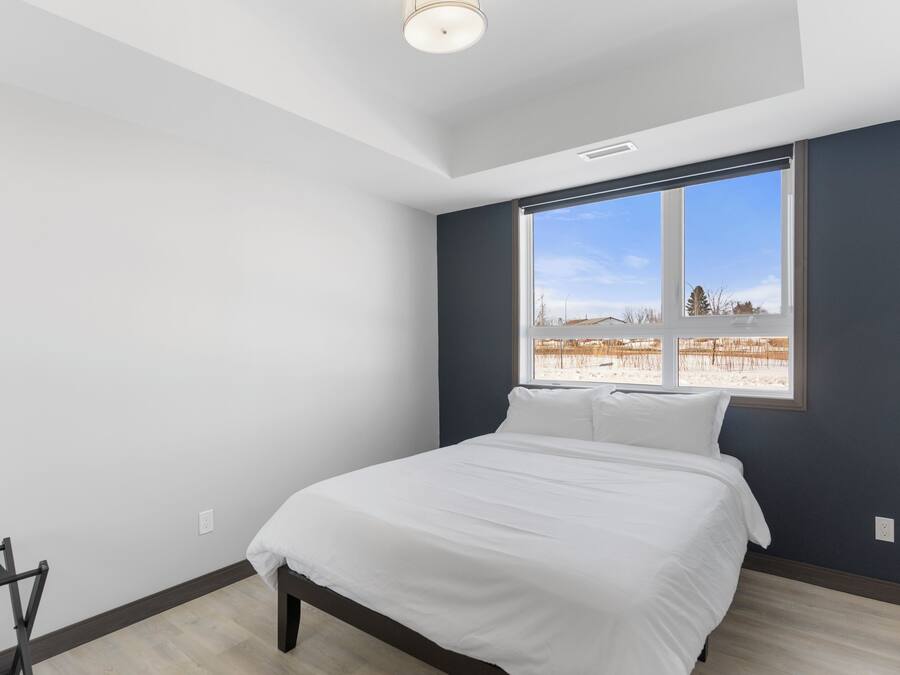 A bedroom with a bed, a window, and a view of a landscape.
