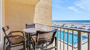 A balcony with a pool, chairs, and a view of the beach. - Relaxing Oceanfront Condo w/ Balcony, Pool & Direct Beach Access (New Smyrna Beach)