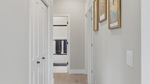 A hallway with white doors, a light-colored wall, and framed artwork.