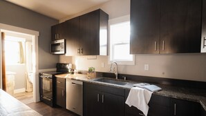 A modern kitchen with dark cabinets, a stainless steel microwave, and a granite countertop. - Family-Friendly Cabin with Hot Tub, Sauna, Firepit with Loft, Sleeps 12 (Crosslake)