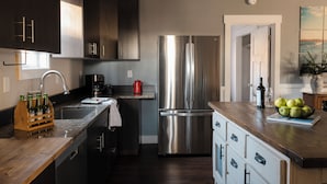 A modern kitchen with stainless steel appliances, a wooden countertop, and a view of the city. - Family-Friendly Cabin with Hot Tub, Sauna, Firepit with Loft, Sleeps 12 (Crosslake)