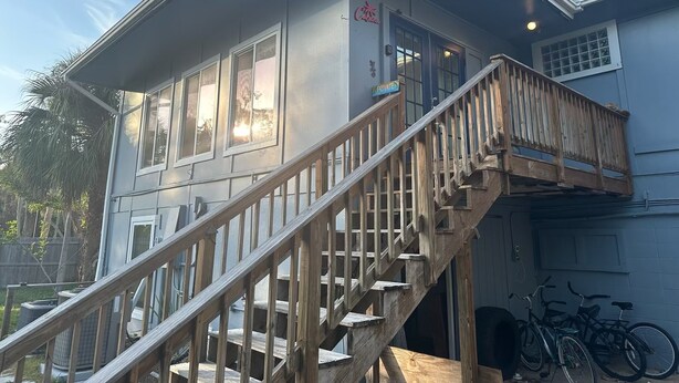 A two-story building with a wooden staircase leading to a balcony. - Siesta Key APT On OceanW/FREE WIFI, BEACH AMENTITIES, ONSITE MANAGER, &LAUNDRY (Siesta Key)