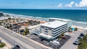 Um hotel à beira-mar com estacionamento, vista para o oceano e uma rua em primeiro plano.