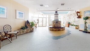 Um hall amplo com lareira de pedra, assentos confortáveis e obras de arte emolduradas nas paredes.