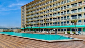 Um hotel com piscina, várias varandas e um espaço de deck com azulejos.