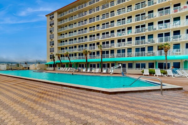 A hotel with a swimming pool, multiple balconies, and a tiled deck area. - Oceanfront Studio w/ Balcony, Pool & Hot Tub Access (Daytona Beach)