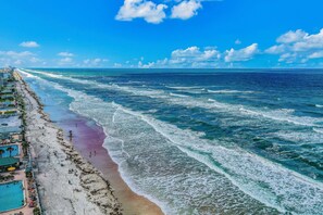 Stunning aerial view of the coastline showcasing rolling waves, soft sands, and endless blue horizons—perfect for enjoying a true beach stay experience. - Cozy Oceanfront Studio w/ Kitchenette & Beach Access in Daytona (Daytona Beach)