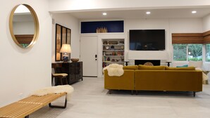 Ein modernes Wohnzimmer mit Sofa, Bank, Fernseher und Kamin.