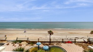 A beach view with a pool, palm tree, and beach chairs. - Oceanfront Studio with Balcony Views & Walkable to Daytona Attractions (Daytona Beach)