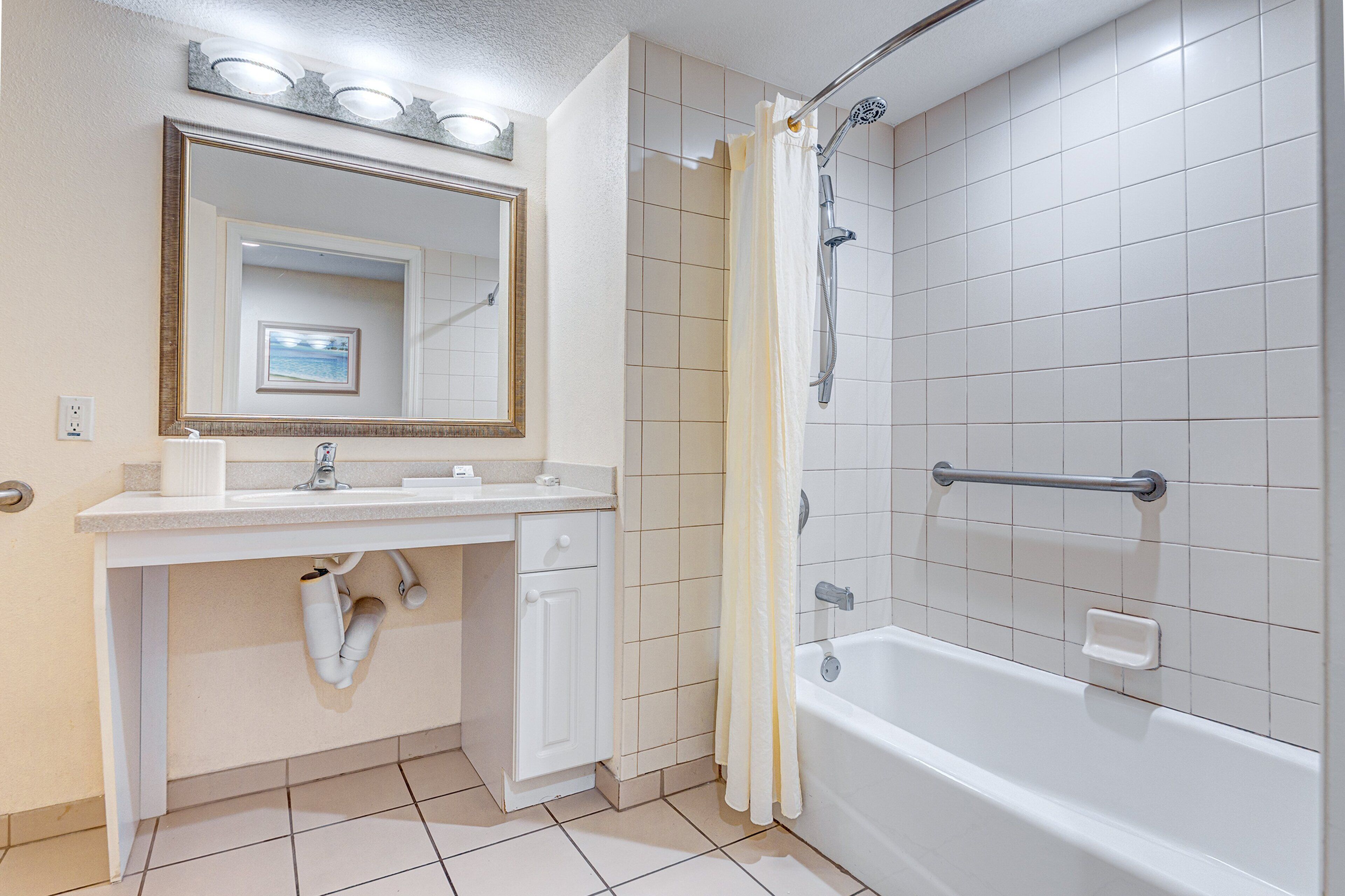 A bathroom with a white sink, mirror, and bathtub.