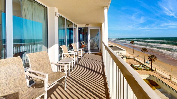 Ein Balkon mit Korbmöbeln und Blick auf den Strand.