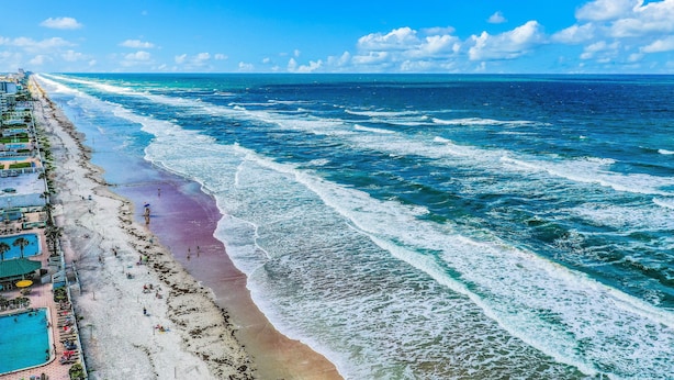 Un complexe hôtelier de bord de mer doté d’une longue plage de sable, d’une piscine et d’une vue sur l’océan.