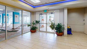 A spacious lobby with a tiled floor, glass doors leading to other areas, and potted plants. - Chic Oceanfront Studio with Balcony, Pool & Direct Beach Access (Daytona Beach)