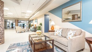 Eine moderne Lobby mit einem Glastisch, einem beigefarbenen Sofa und einer blauen Akzentwand.