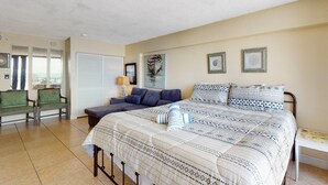 A bedroom with a large bed, a sofa, a chair, and a small table.
